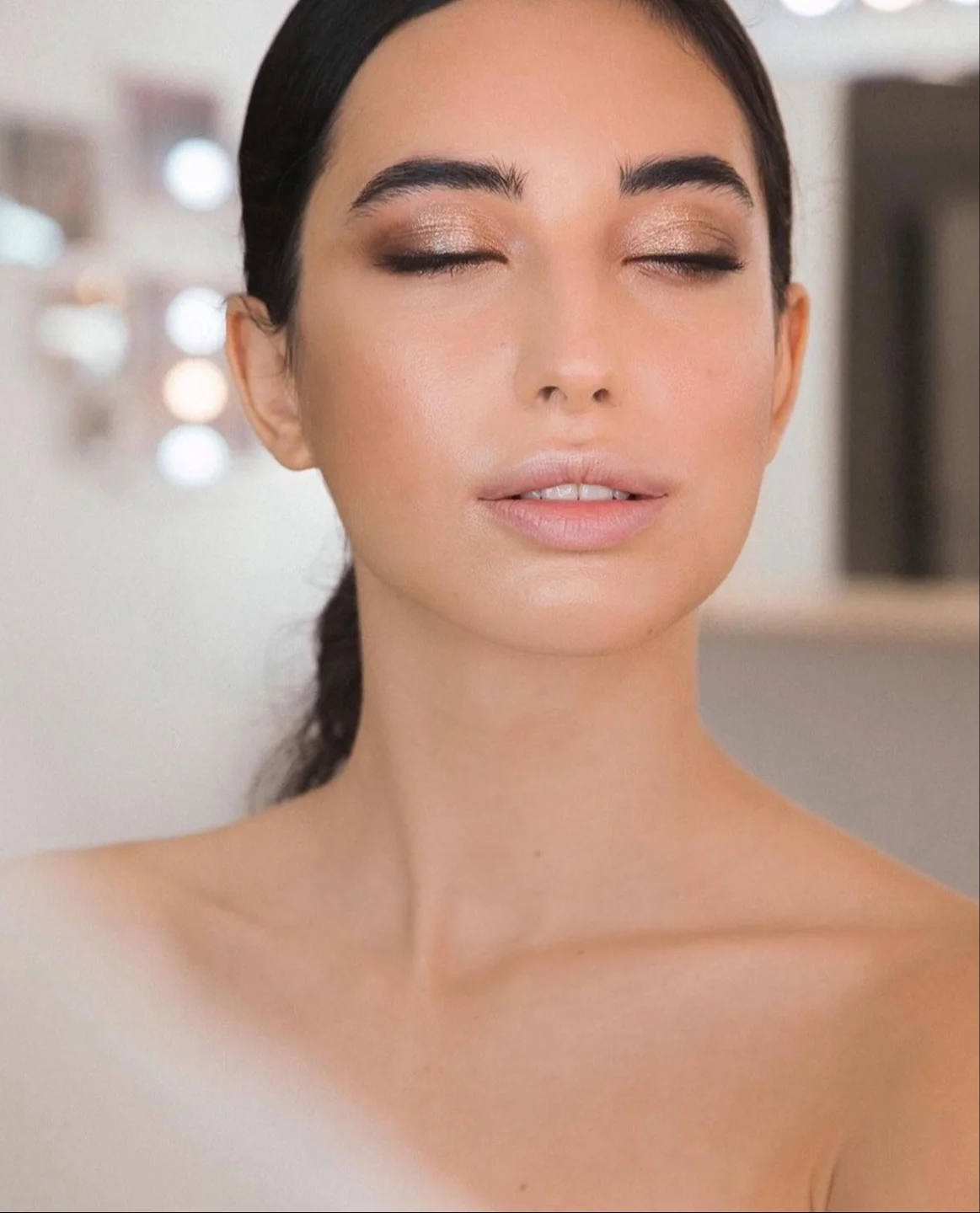 Primer plano de maquillaje natural con sombras cálidas y ojos cerrados